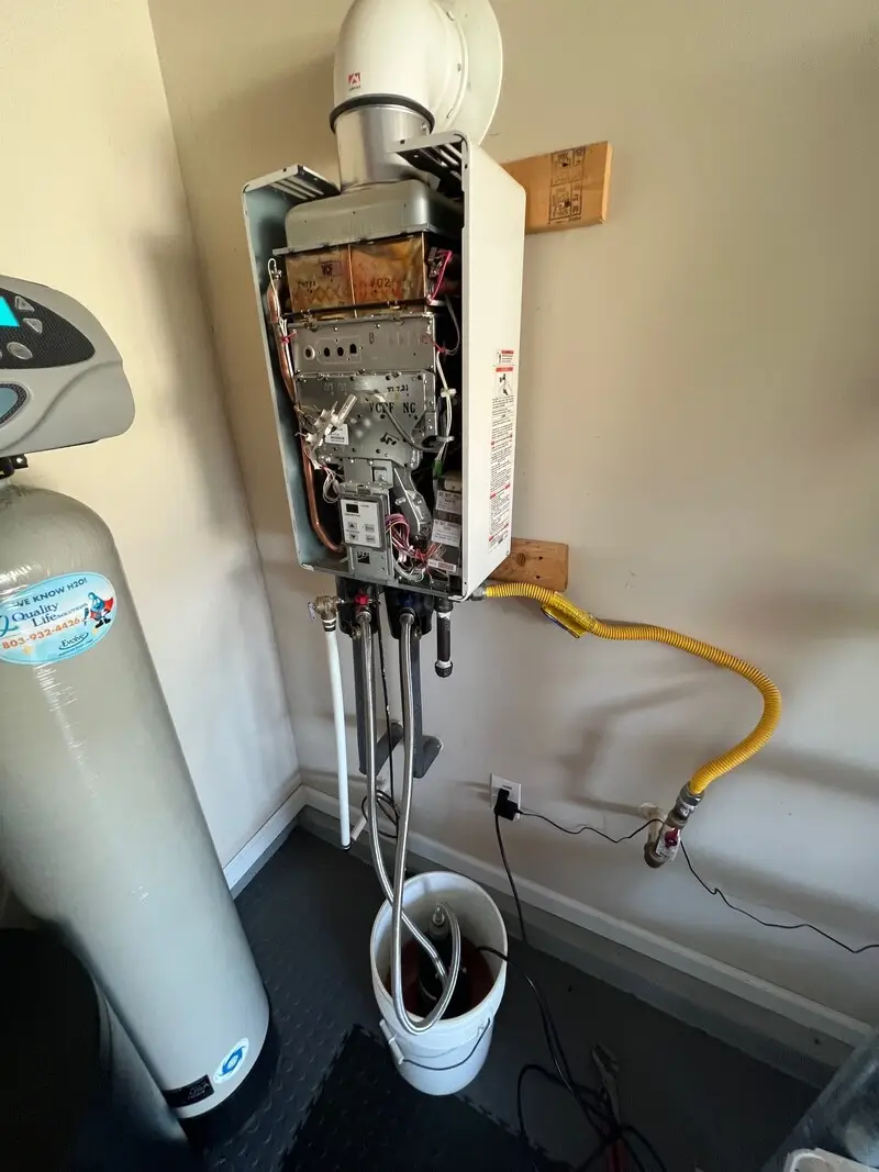 Indoor tankless water heater with its cover removed during service