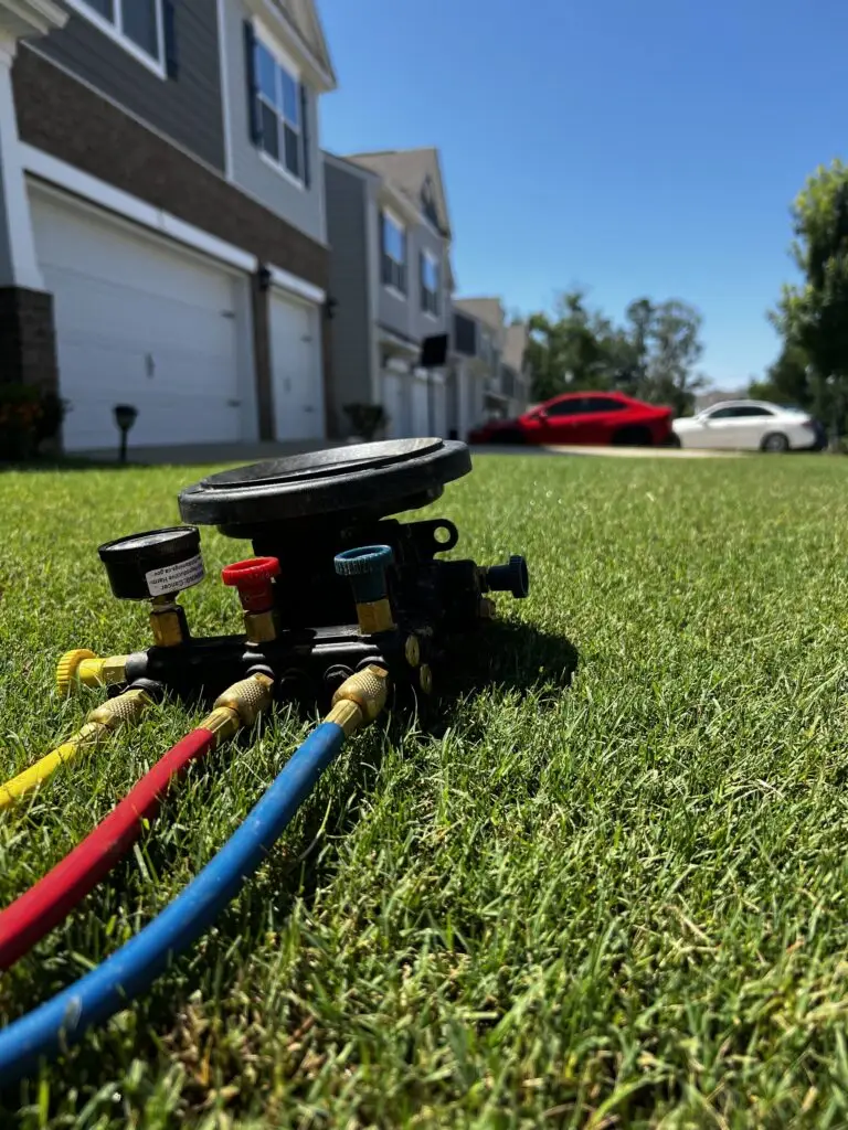 Backflow test kit with pressure gauge and red, yellow and blue test hoses set up on a residential lawn