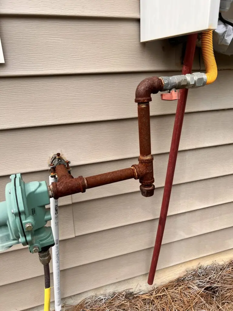 Rusted gas supply line beside a gas meter before protective painting