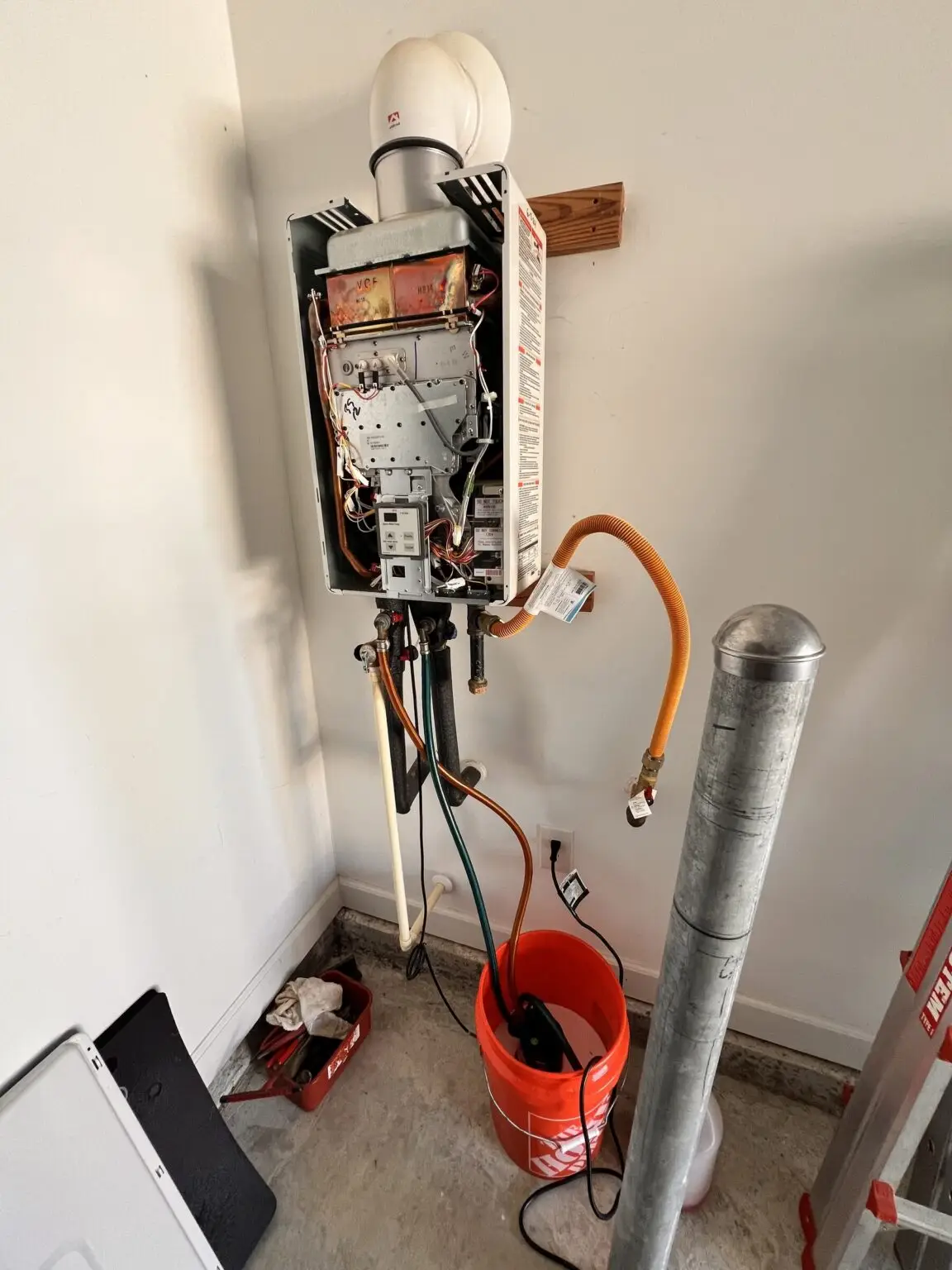 Indoor tankless water heater with its cover removed and hoses connected during a flush and descaling service