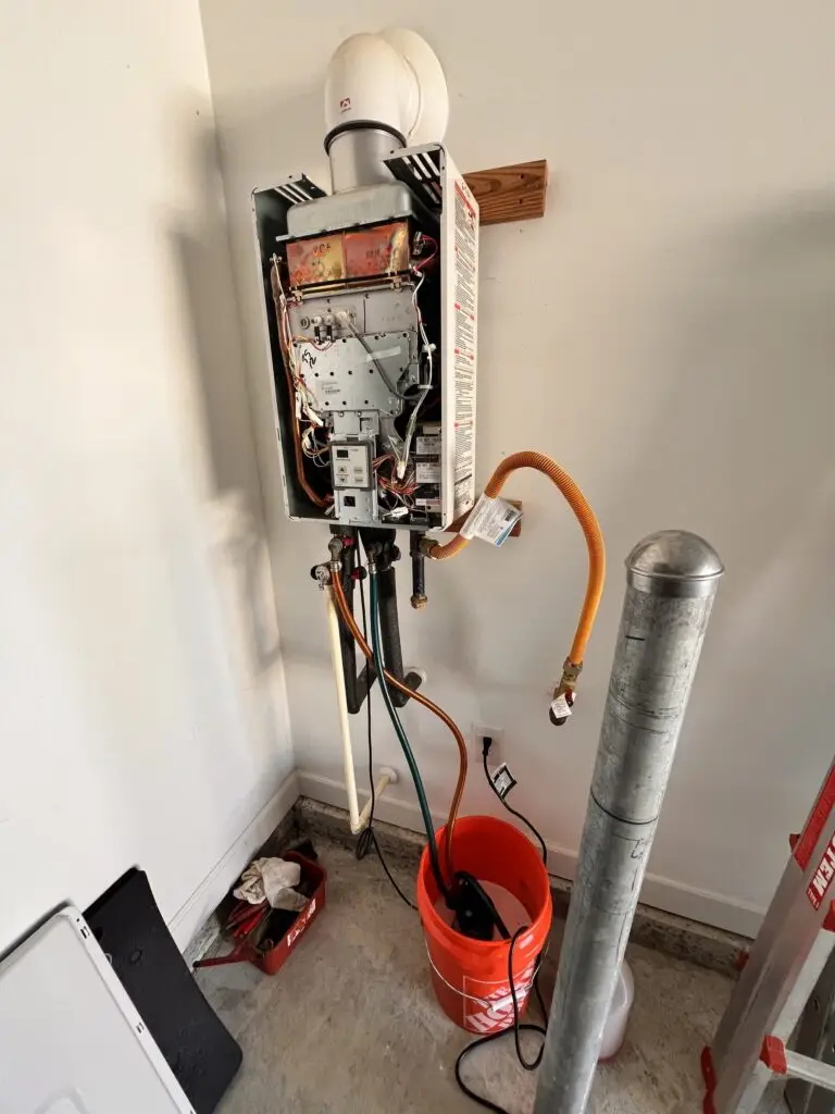Indoor tankless water heater with its cover removed and hoses connected during a flush and descaling service