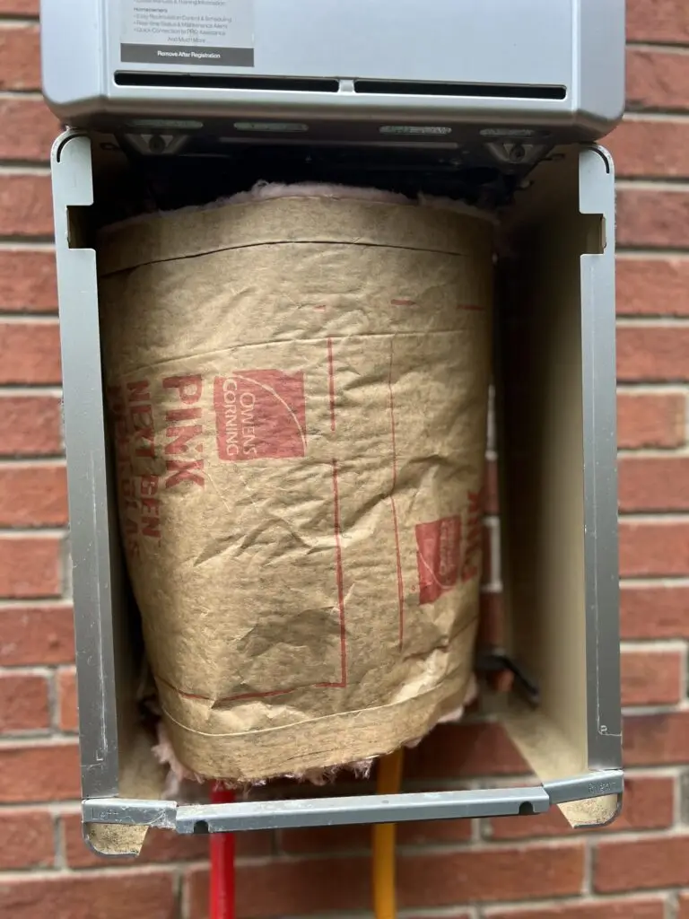 Insulation wrapped around the exposed pipes beneath an outdoor tankless water heater for winter protection