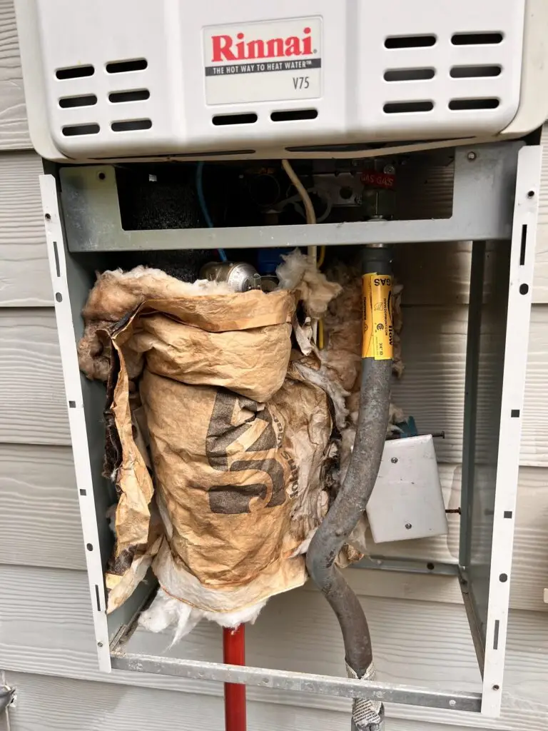 Worn, torn insulation inside an outdoor Rinnai tankless water heater pipe cover before replacement